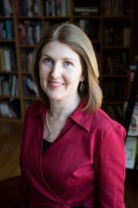 Paralegal sitting on desk in front of book shelf in office