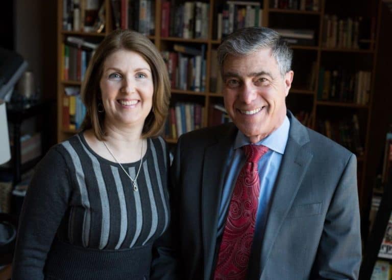 Attorney and paralegal pose in front of bookcase in office